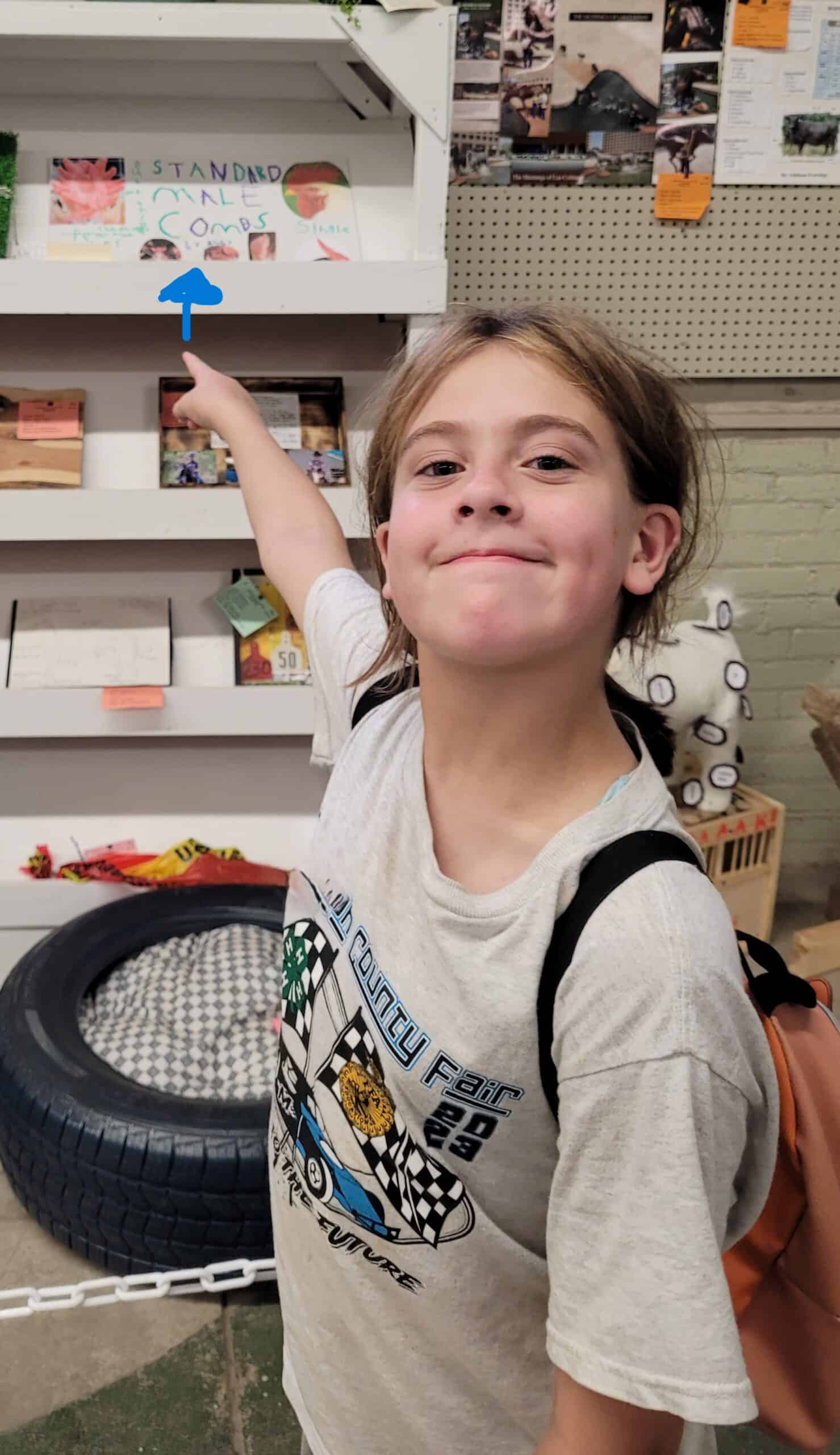 young girl pointing to her chicken poster displayed at the state fair