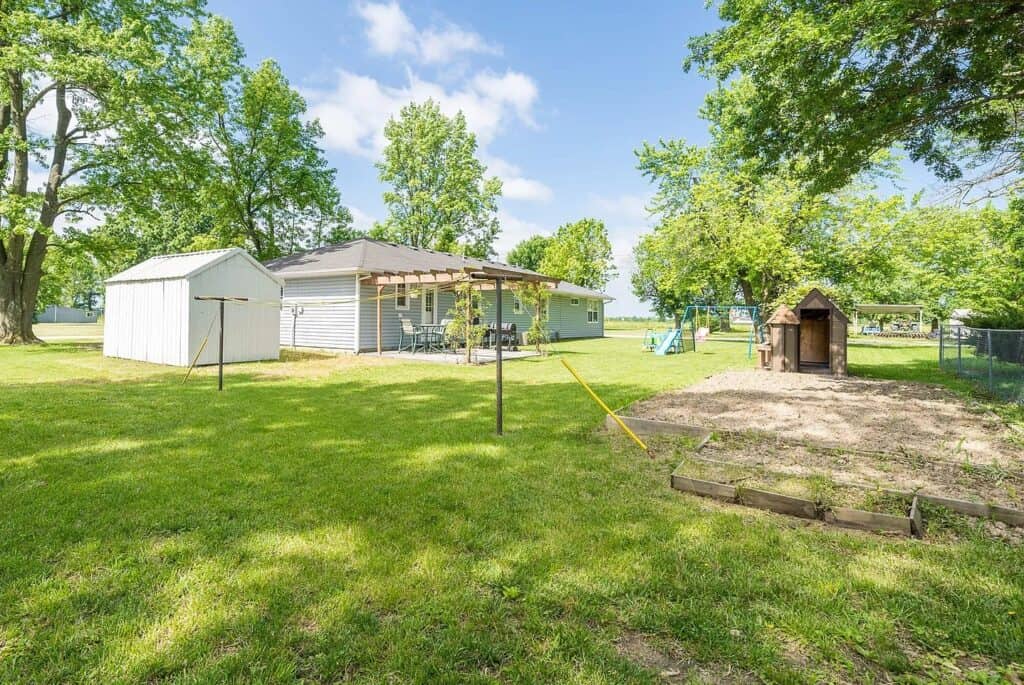 view of a backyard to a ranch style home with a clothes line raised garden beds and a playset