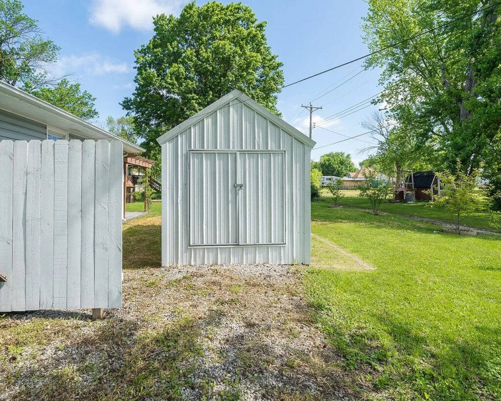 picture of a white metal A frame shed beside a house