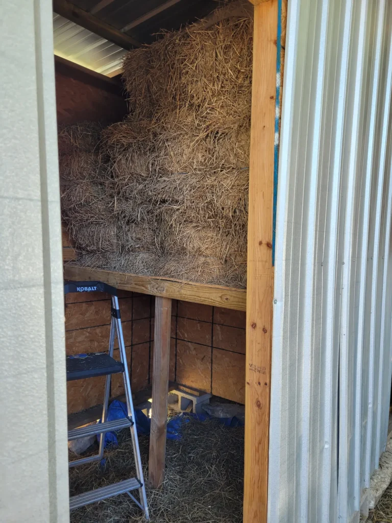 hay loft built into small room - essentially a large flat shelf with several bales of hay sitting on it